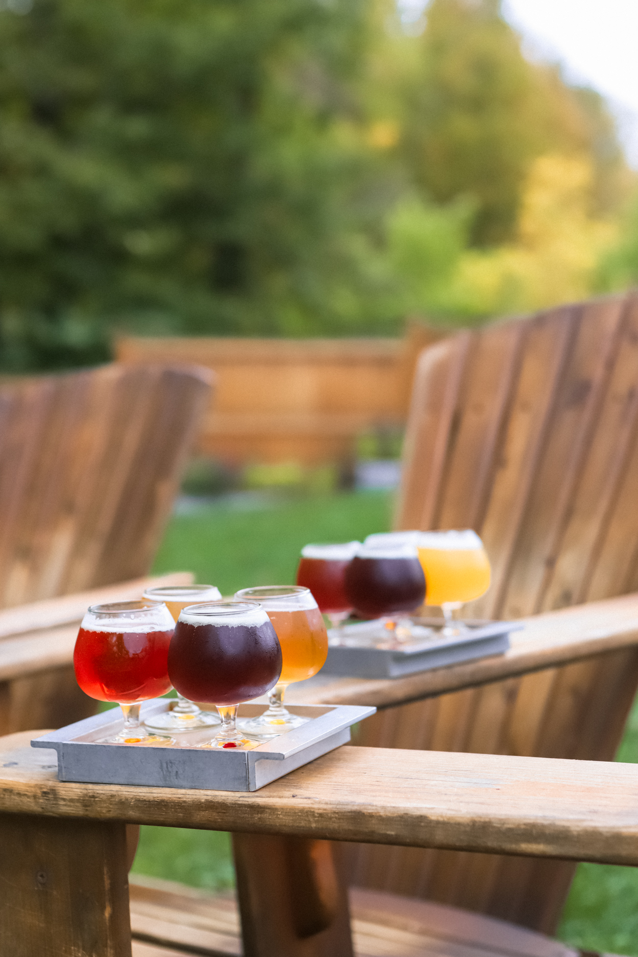 Flight of craft beers on a metal tray on wooden Adirondack chairs at a brewery in Vermont 