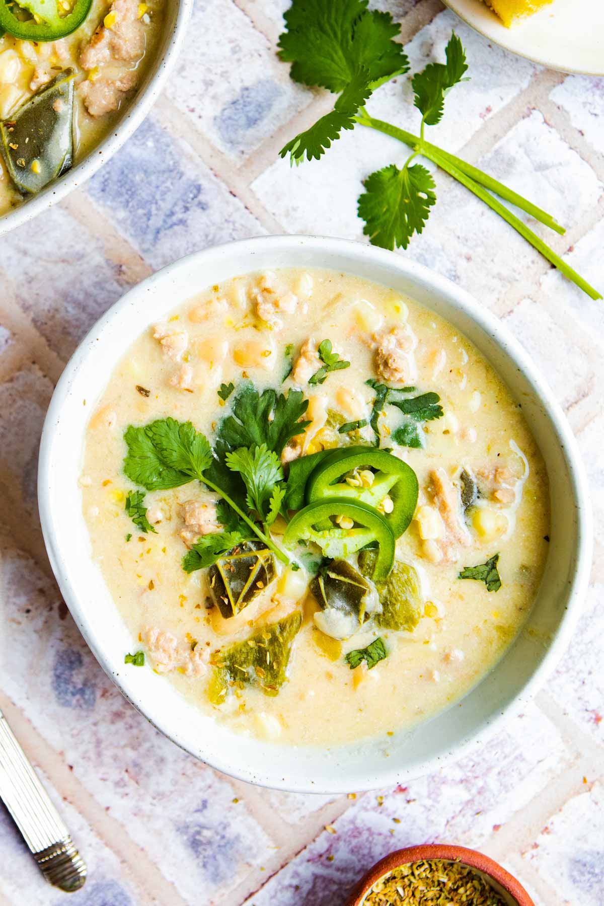 a ceramic bowl filled with white bean chicken chili in the instant pot and garnished with various herbs and jalapenos