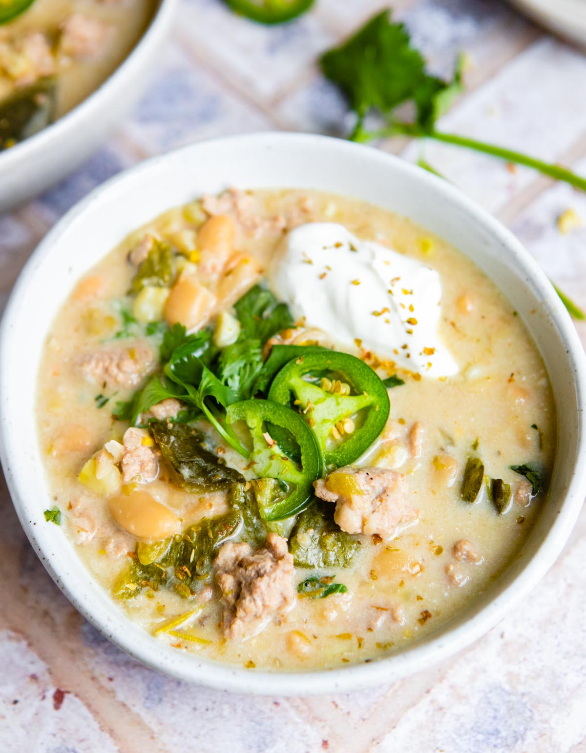 white bean chicken chili topped with sour cream and garnishes served in a ceramic bowl