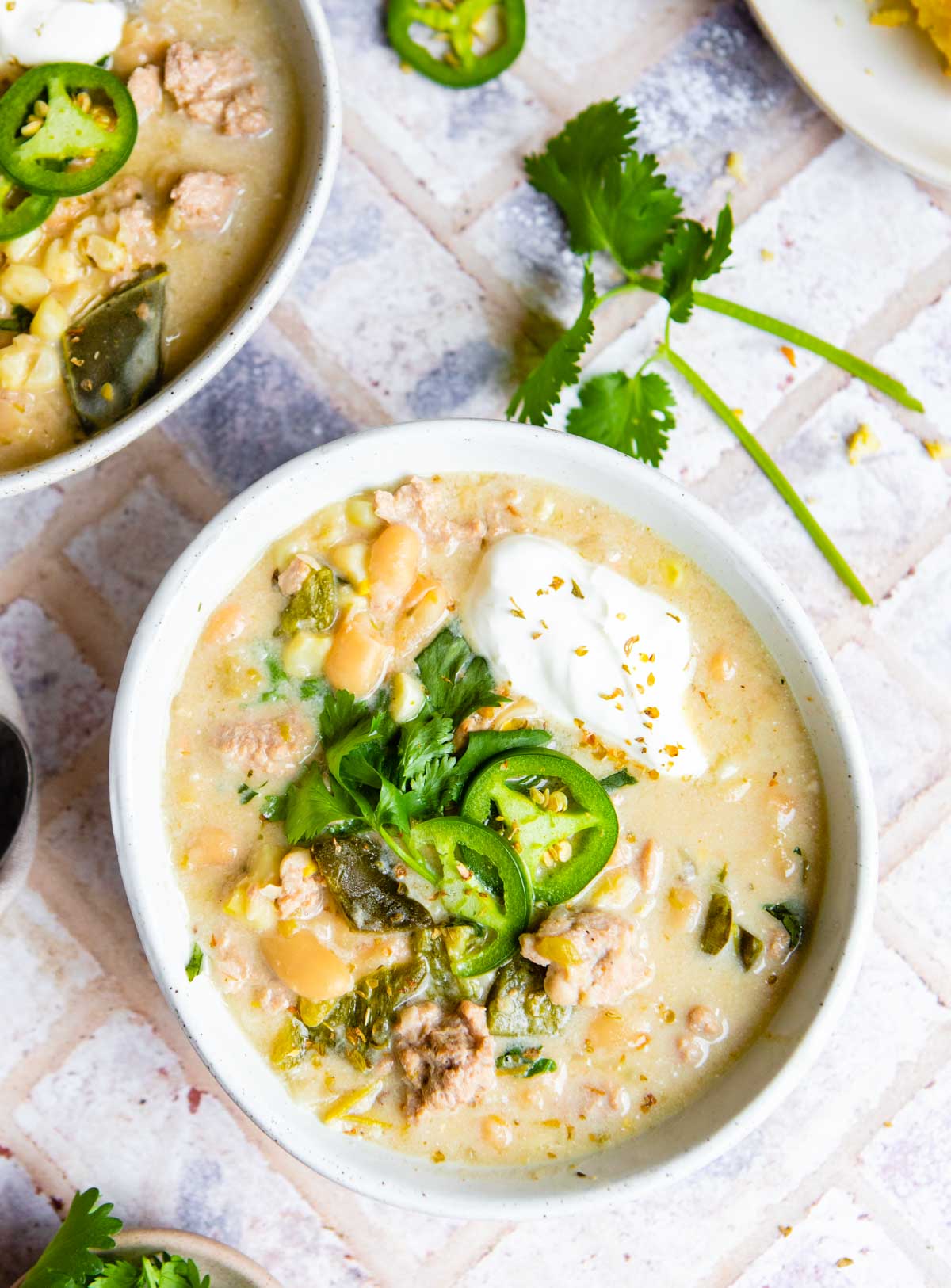 beige ceramic bowls filled with white chicken chili made in the Instant Pot and garnished with jalapenos