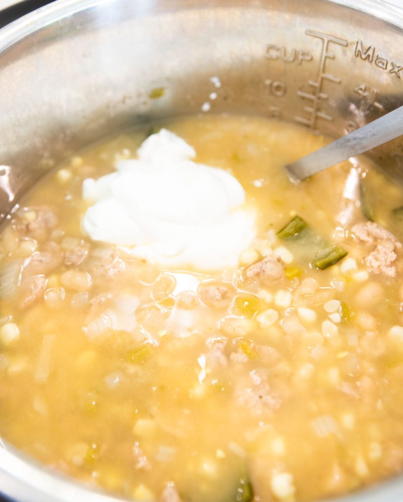 sour cream being stirred into a chicken chili in the Instant Pot