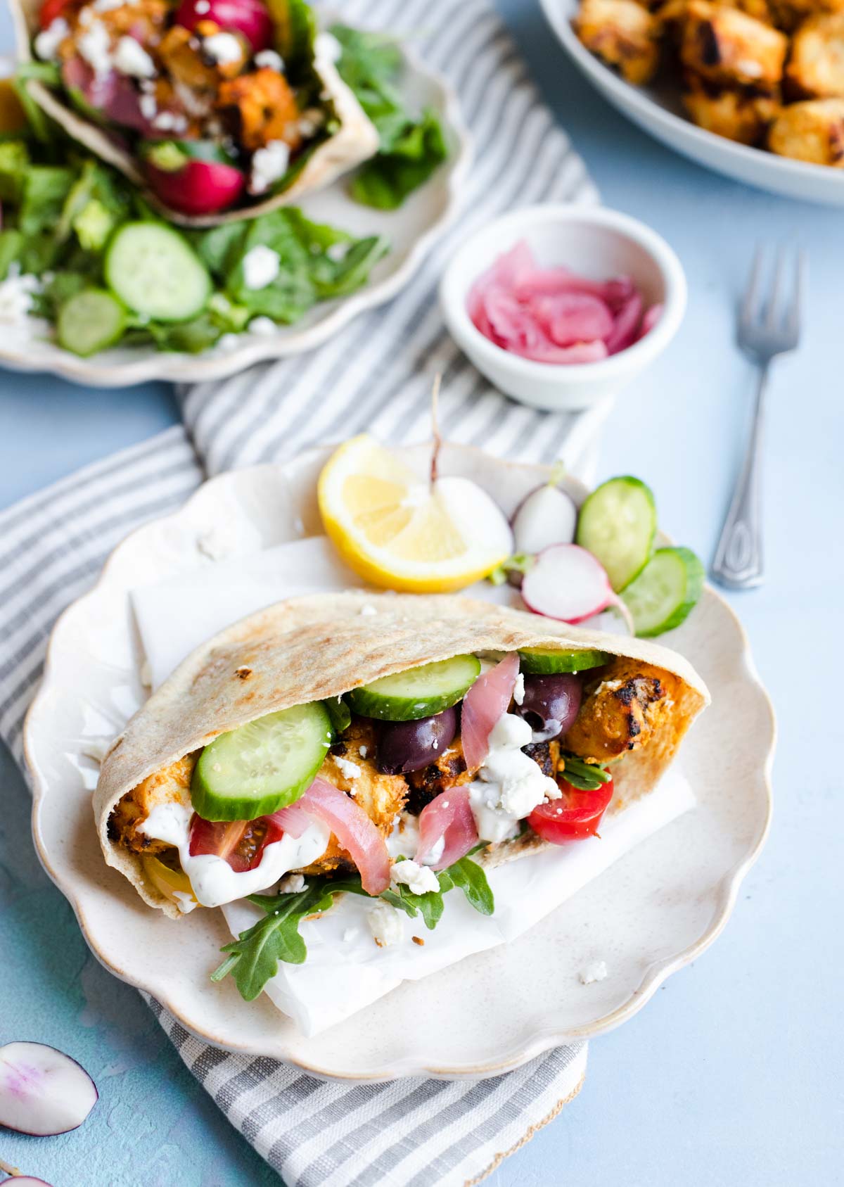 scalloped plates loaded with stuffed pita shawarma and garnishes