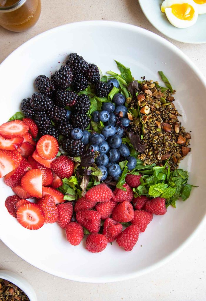 berries, salad greens, mint and crispy quinoa in a large serving bowl