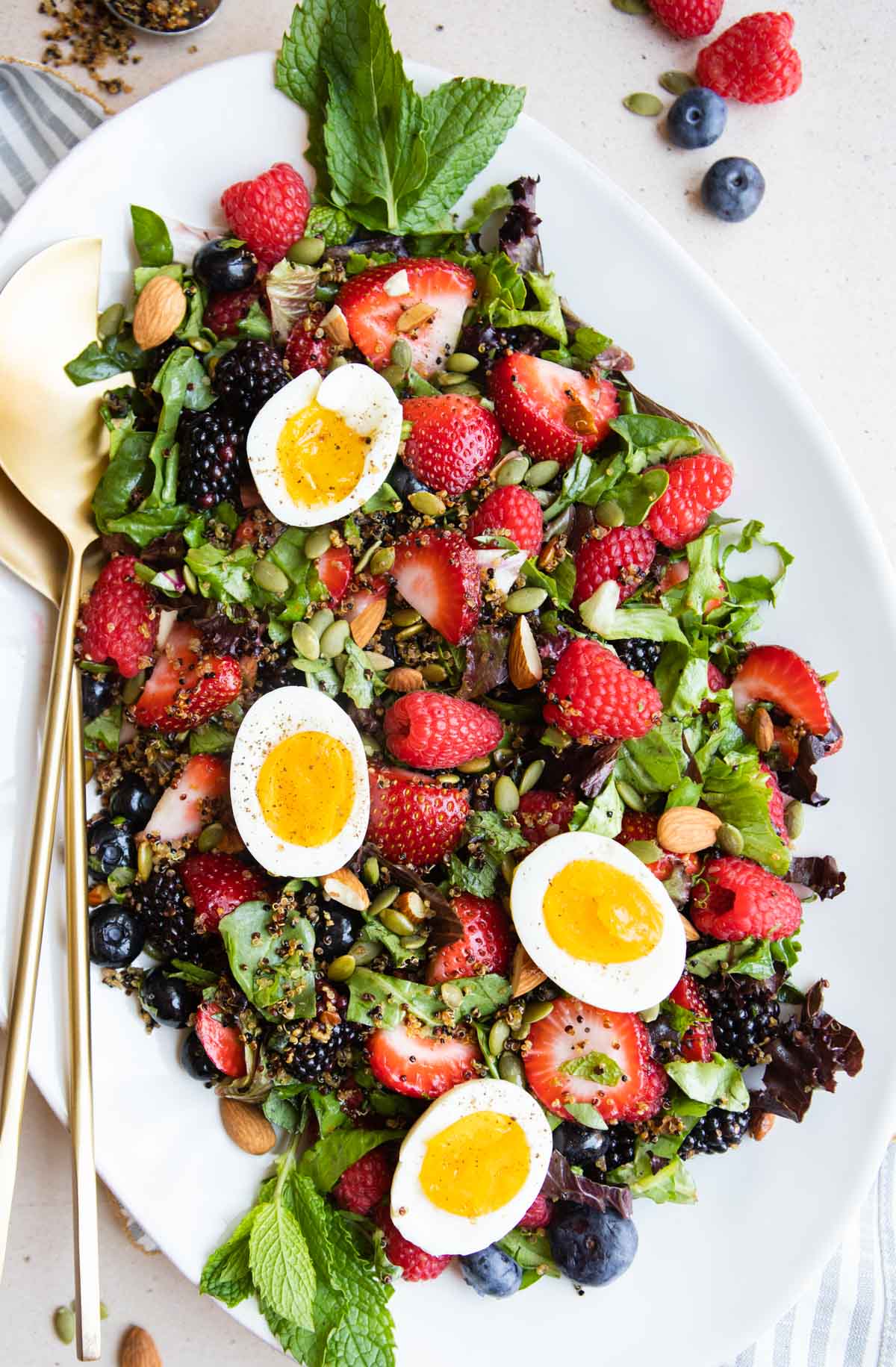 a large white platter filled with a breakfast fruit salad and topped with hard boiled eggs and nuts