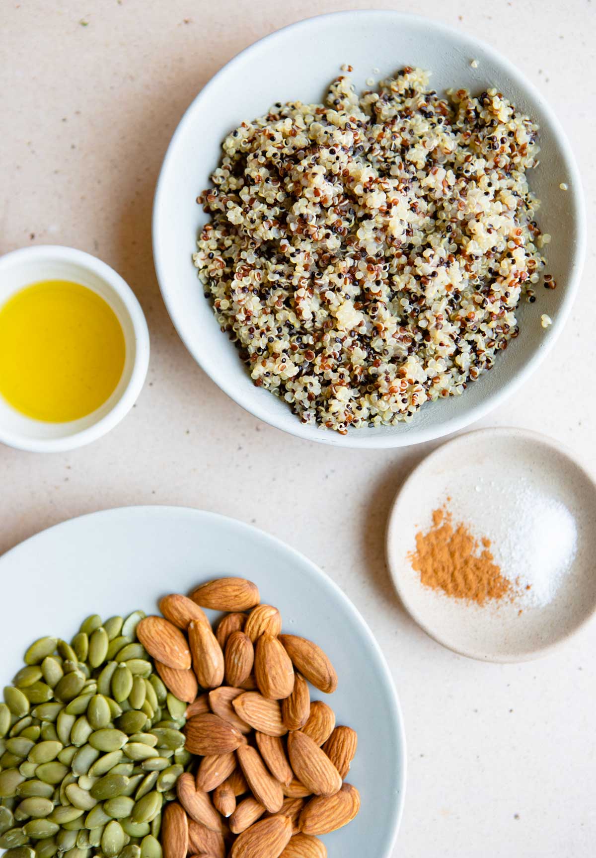 cooked quinoa, nuts and seeds, olive oil, salt and cinnamon in small ceramic dishes