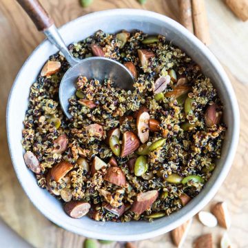 a ceramic bowl filled with crispy quinoa with almonds and pumpkin seeds