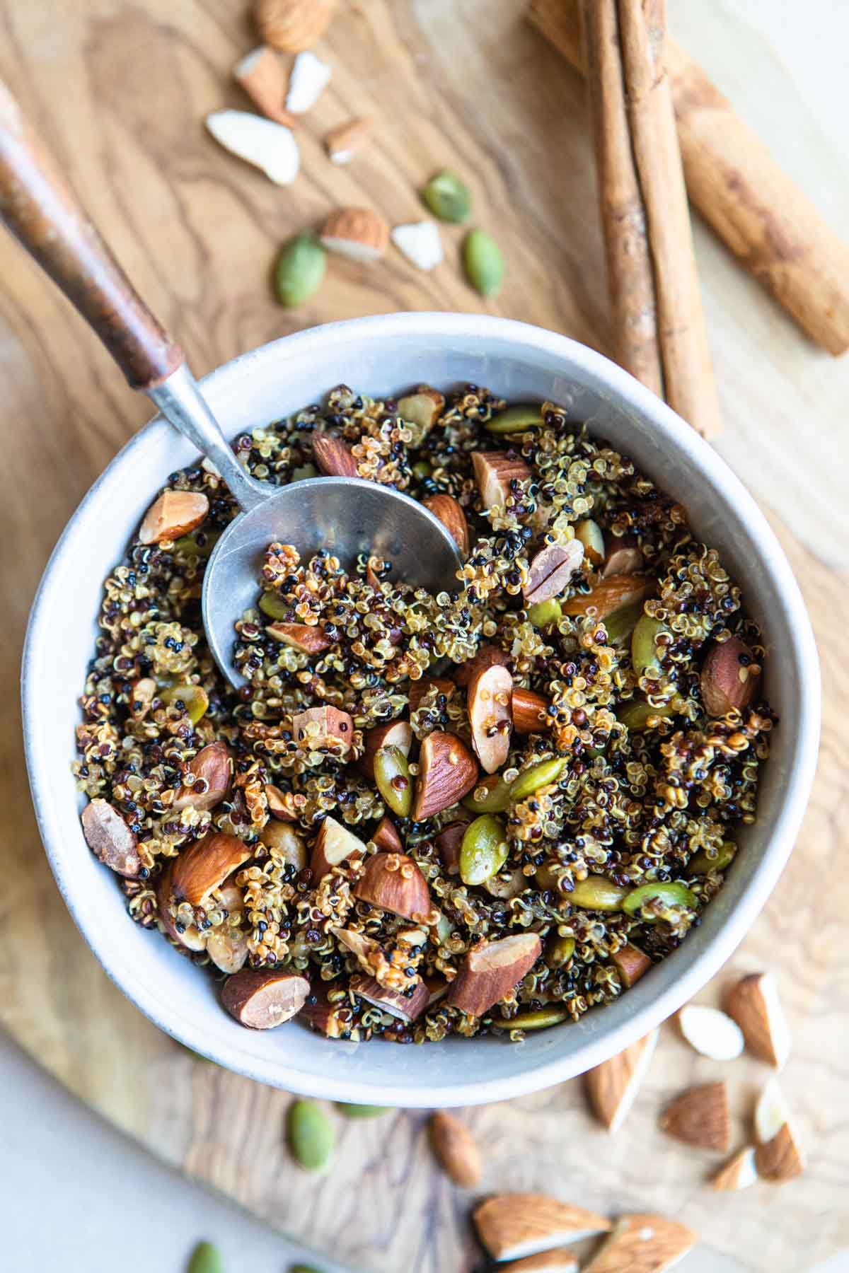 a ceramic bowl filled with nutty crispy quinoa and a wooden serving spoon 