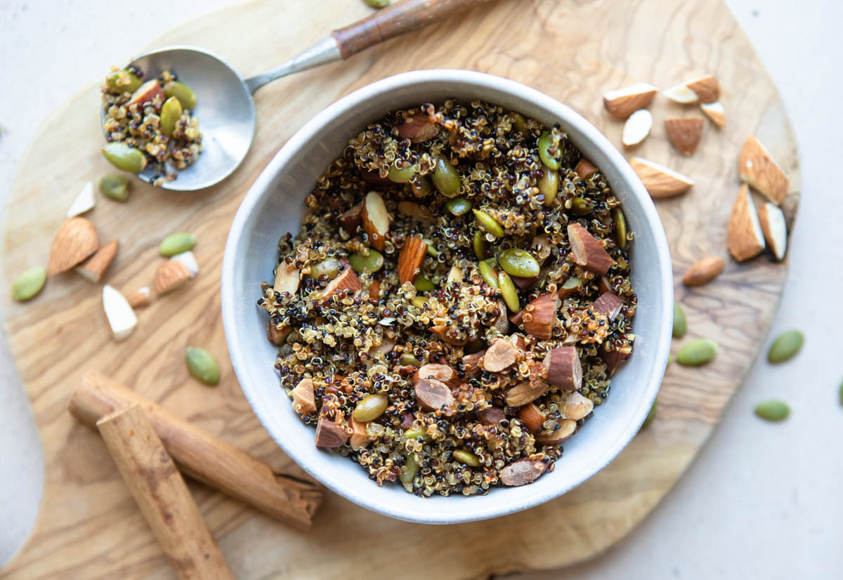 a small bowl filled with crispy quinoa mixed with almonds and pumpkin seeds