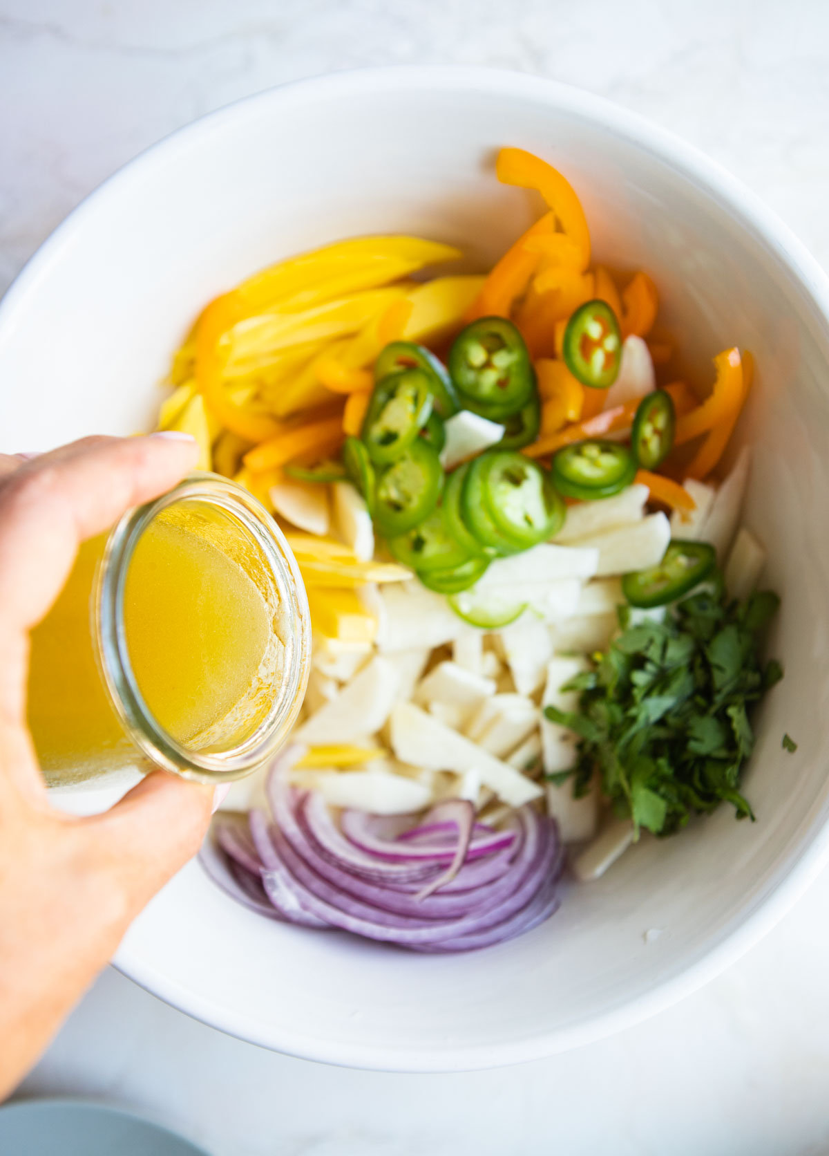 lime vinaigrette being poured on a jicama salad