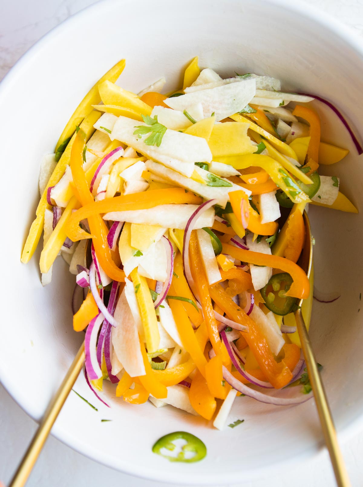 sliced jicama, mango, bell peppers and red onions tossed in a large white serving bowl