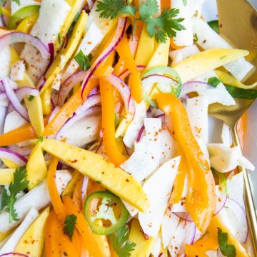 jicama salad with mango, red onions, peppers and jalapeno on a white platter