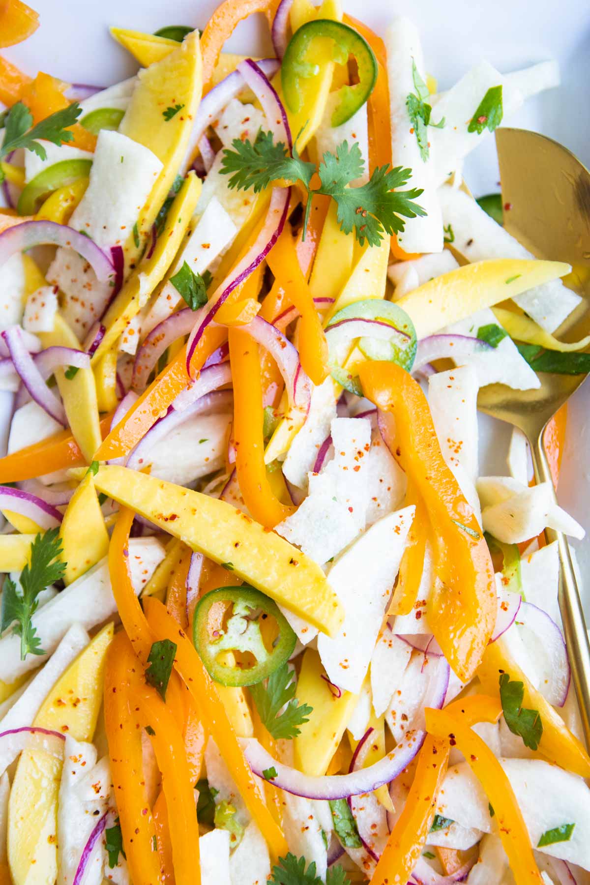 jicama salad with mango, red onions, peppers and jalapeno on a white platter