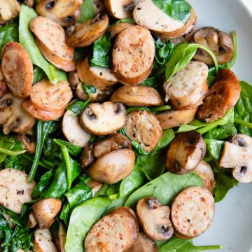 mushrooms, sliced sausages and spinach sauteed and placed in a gray bowl