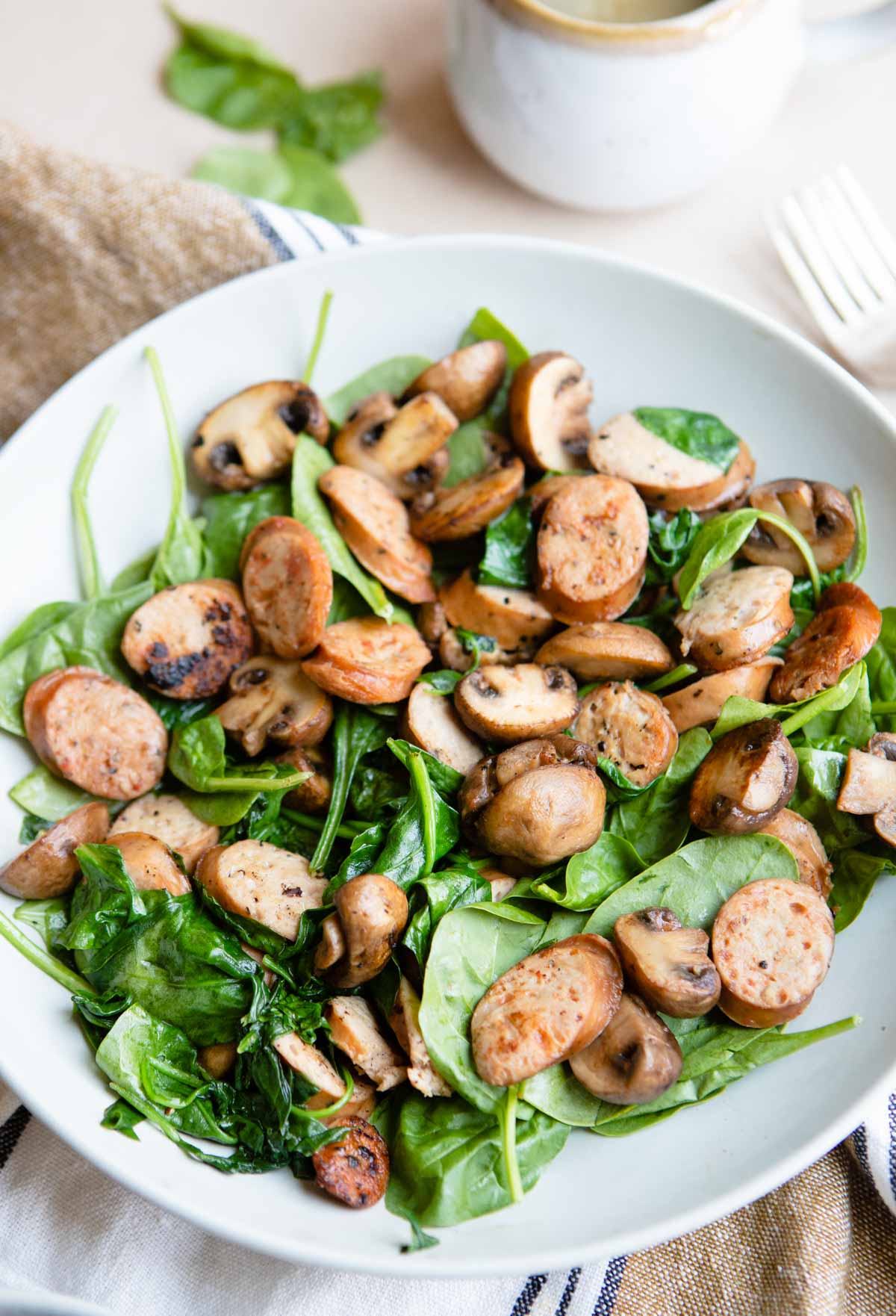 sauteed sausages, mushrooms and spinach cooked and placed in a large gray plate ready to serve