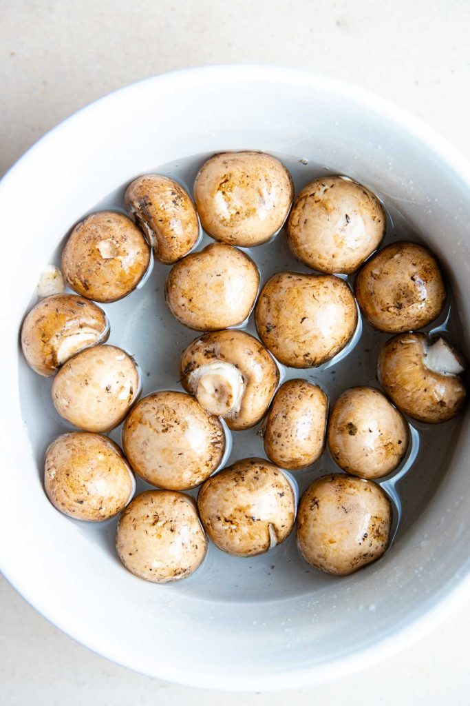 raw baby bella mushrooms soaking in cool water