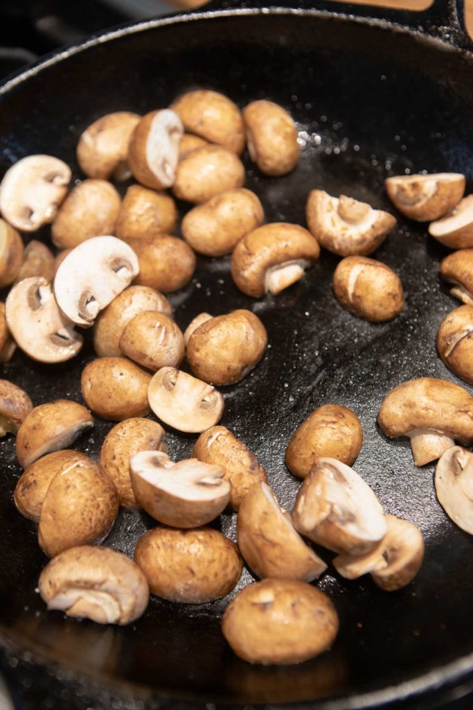 mushrooms sliced cooking in a cast iron skillet