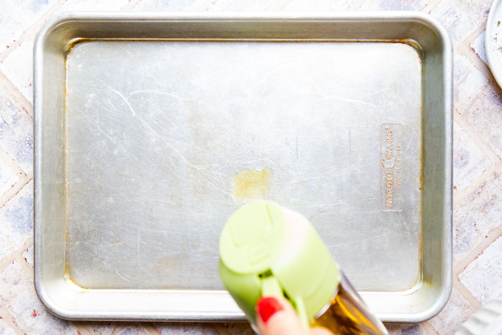 ¼ sheet pan being sprayed with cooking oil