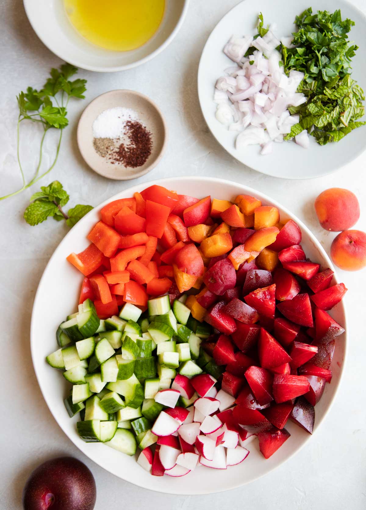 ingredients to make a stone fruit salad with summer vegetables on a white platter