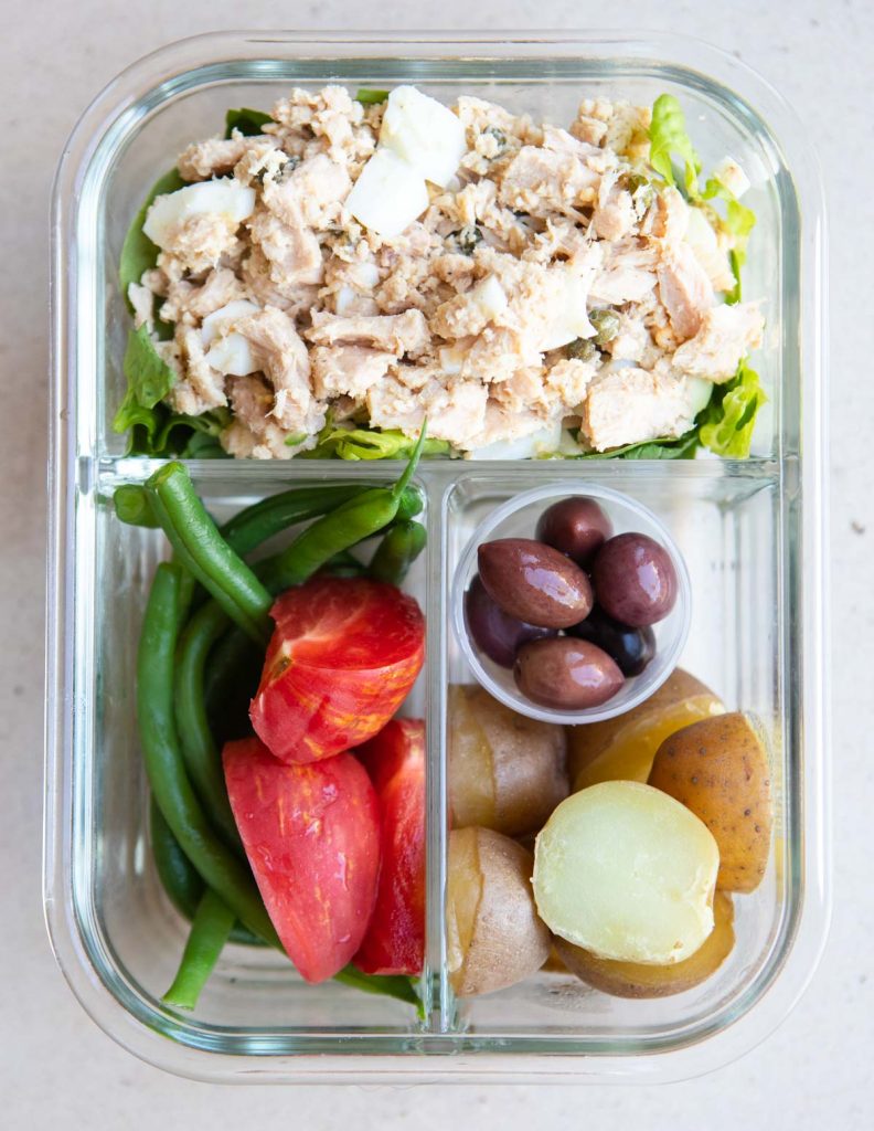 tuna salad, green beans, tomatoes, boiled potatoes and kalamata olives in a glass meal prep container 