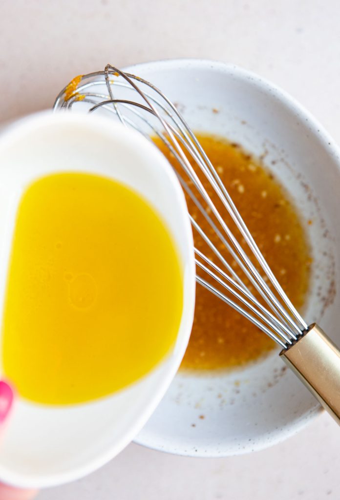 olive oil being whisked in to orange juice to make an orange vinaigrette