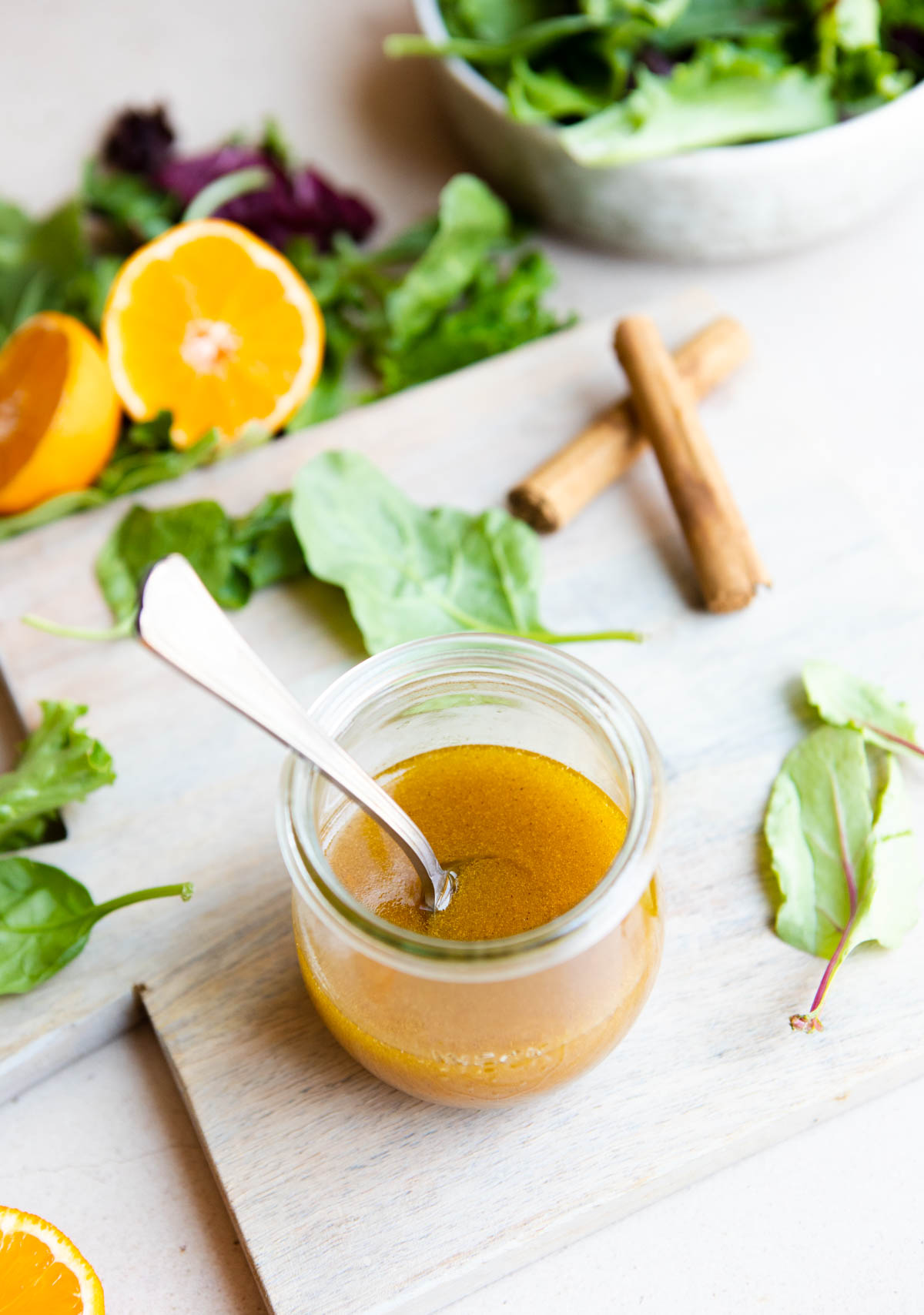 a glass of maple orange salad dressing on a wood board