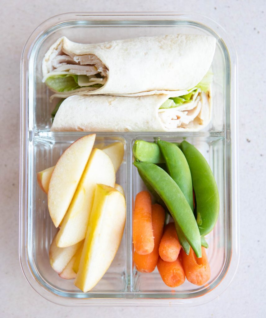 turkey sandwich wrap with apples, sugar snap peas and carrots, in a glass meal prep container