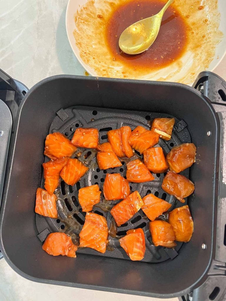 raw marinated salmon bites in the basket of an air fryer