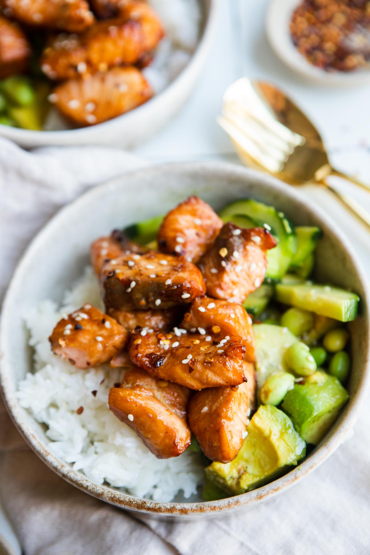 a beige bowl filled with white rice edamame salad and teriyaki salmon air fryer bites