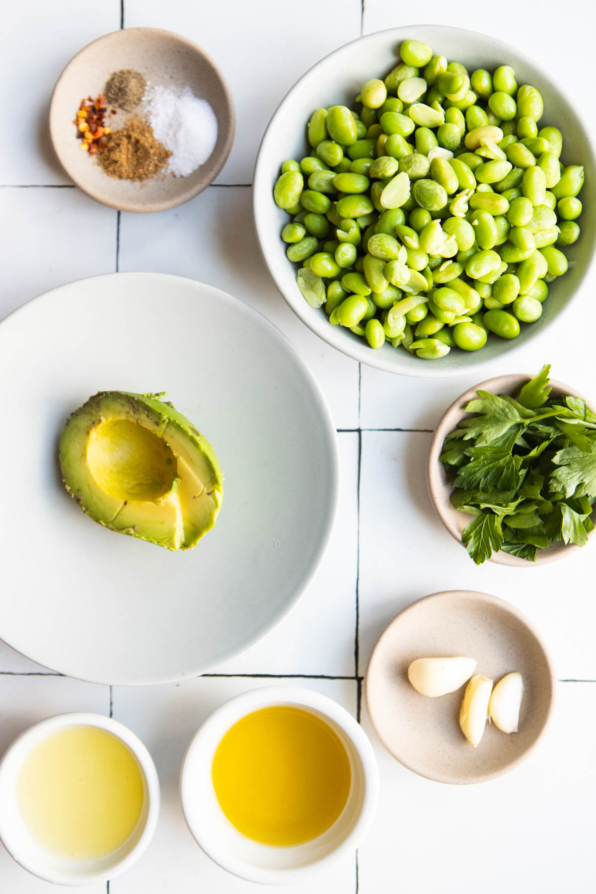 ingredients to make edamame and avocado hummus in small white and beige bowls