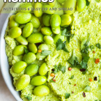 bowl of edamame hummus garnished with parsley, red chili flakes and shelled edamame