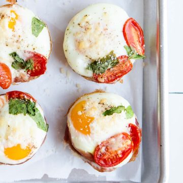 prosciutto cups garnished with parmesan cheese and basil on a parchment lined baking sheet