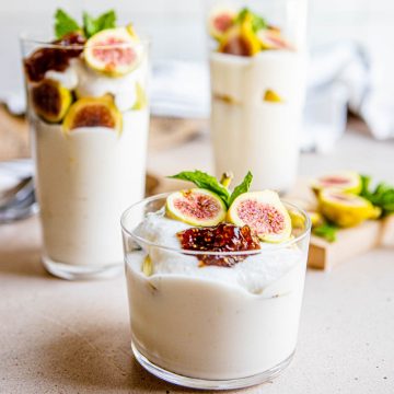 3 clear glasses filled with ricotta dessert and topped with figs