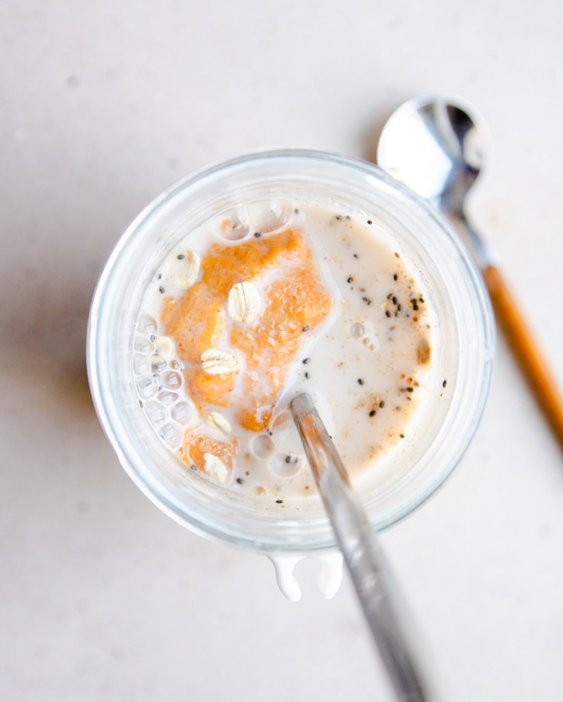 milk and pumpkin puree added to a mason jar with overnight oats in it