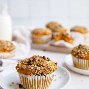 protein muffins pumpkin flavored and topped with a pepita streusel topping and set on a white surface.