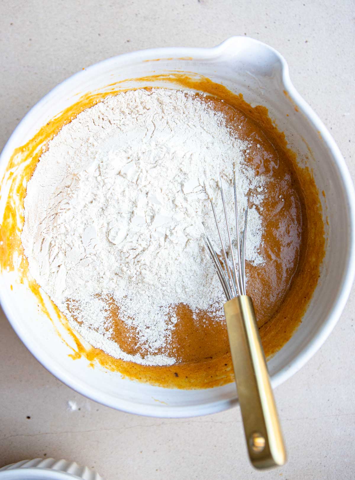 flour and pumpkin puree mixture combined in a large white mixing bowl