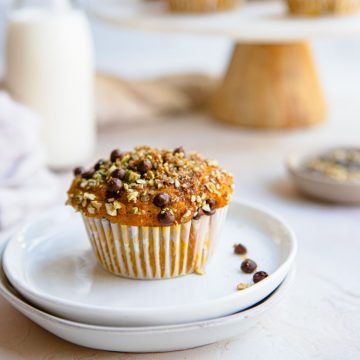 a pumpkin protein muffin on a white plate and garnished with dark chocolate chips