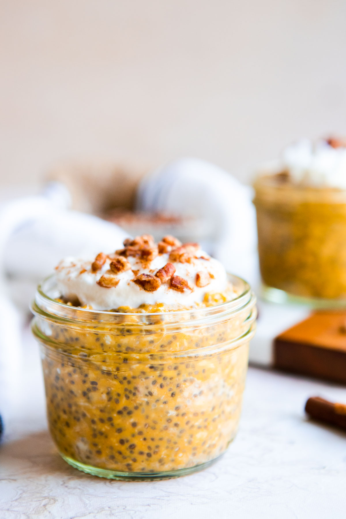 an 8 ounce mason jar filled with pumpkin protein oats and topped with a bit of whipped cream and crushed pecans