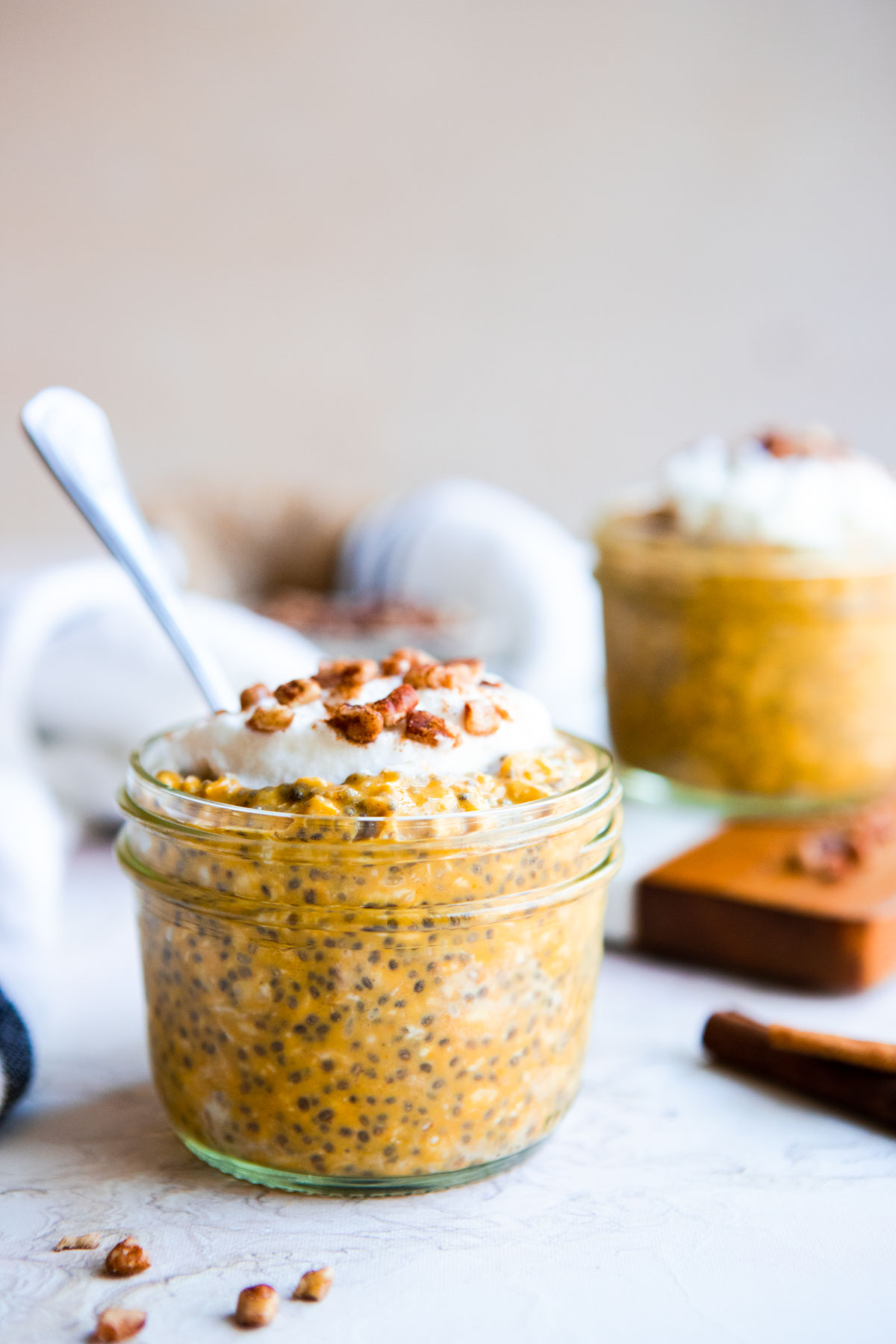 2 mason jars filled with pumpkin spice overnight oats and topped with cream and pecans