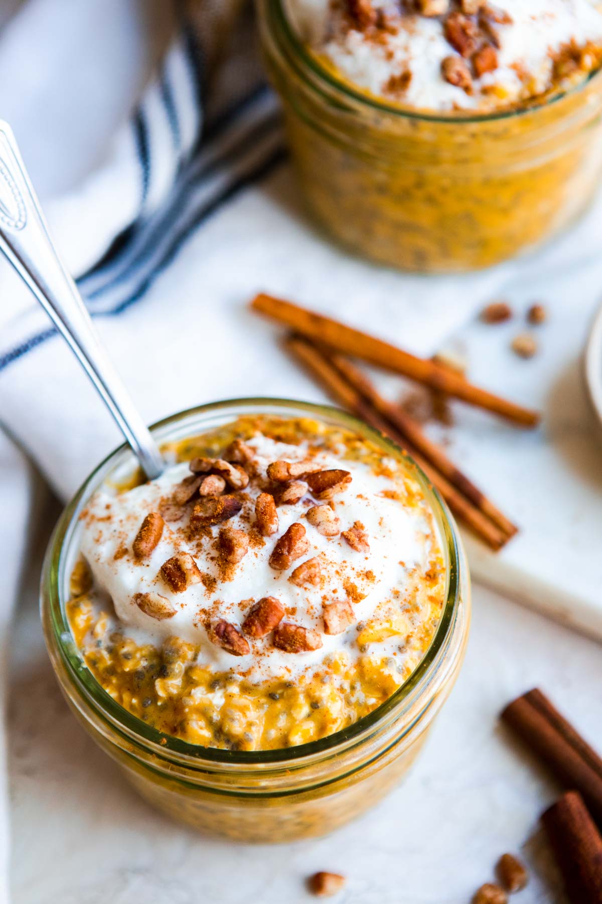 a jar of overnight oats that are topped with whipped cream and pecan pieces