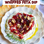 cranberry whipped feta dip on a plate garnished with walnuts and rosemary