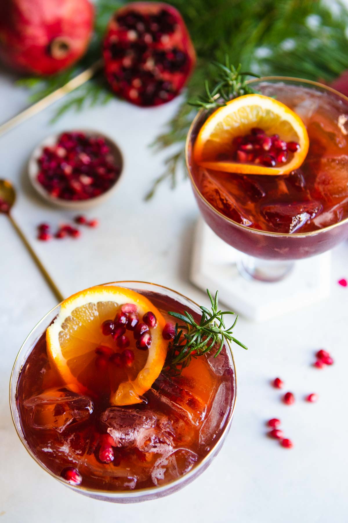 glasses filled with pomegranate sprtizer and garnished with orange slices and rosemary