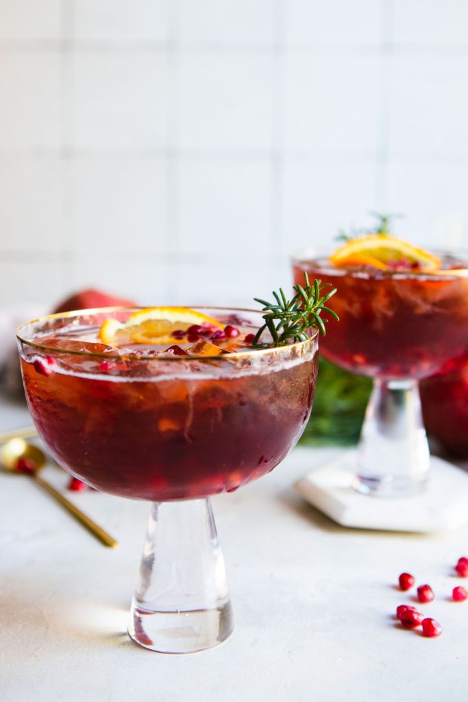 2 pink glasses filled pomegranate spritz and garnishes 