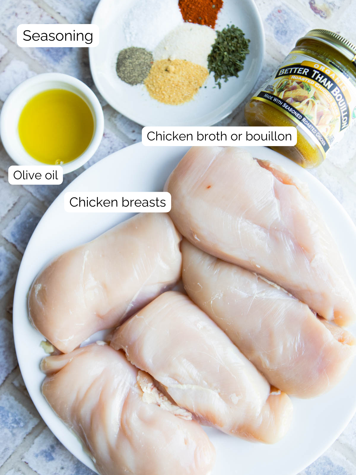 raw chicken breasts, olive oil and dried seasonings on a platter 