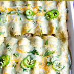 a pan of chicken enchiladas covered with green enchilada sauce and cheese