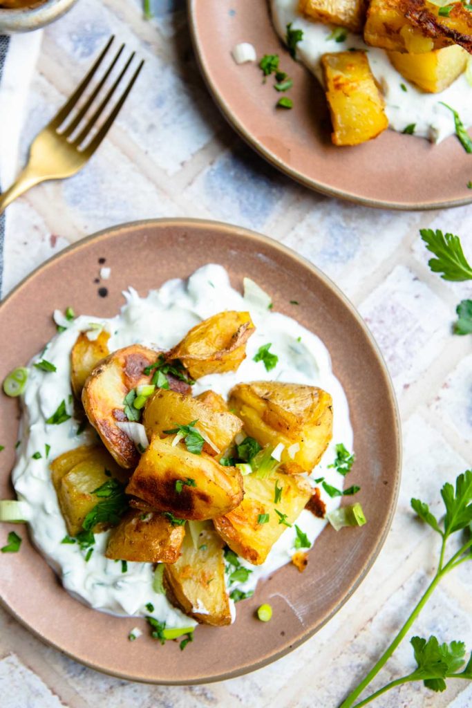 a plate filled with tangy greek yogurt sauce and roasted baby dutch yellow potatoes