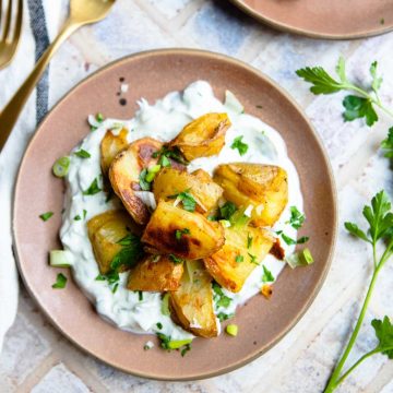 brown plate filled with Greek yogurt sauce and roasted baby potatoes