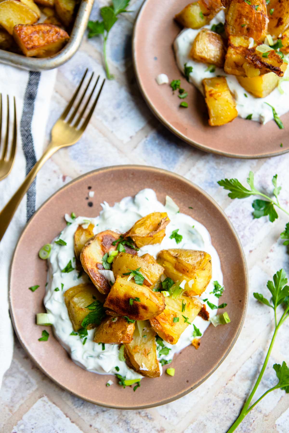 2 brown plates with a yogurt spread and roasted potatoes on top