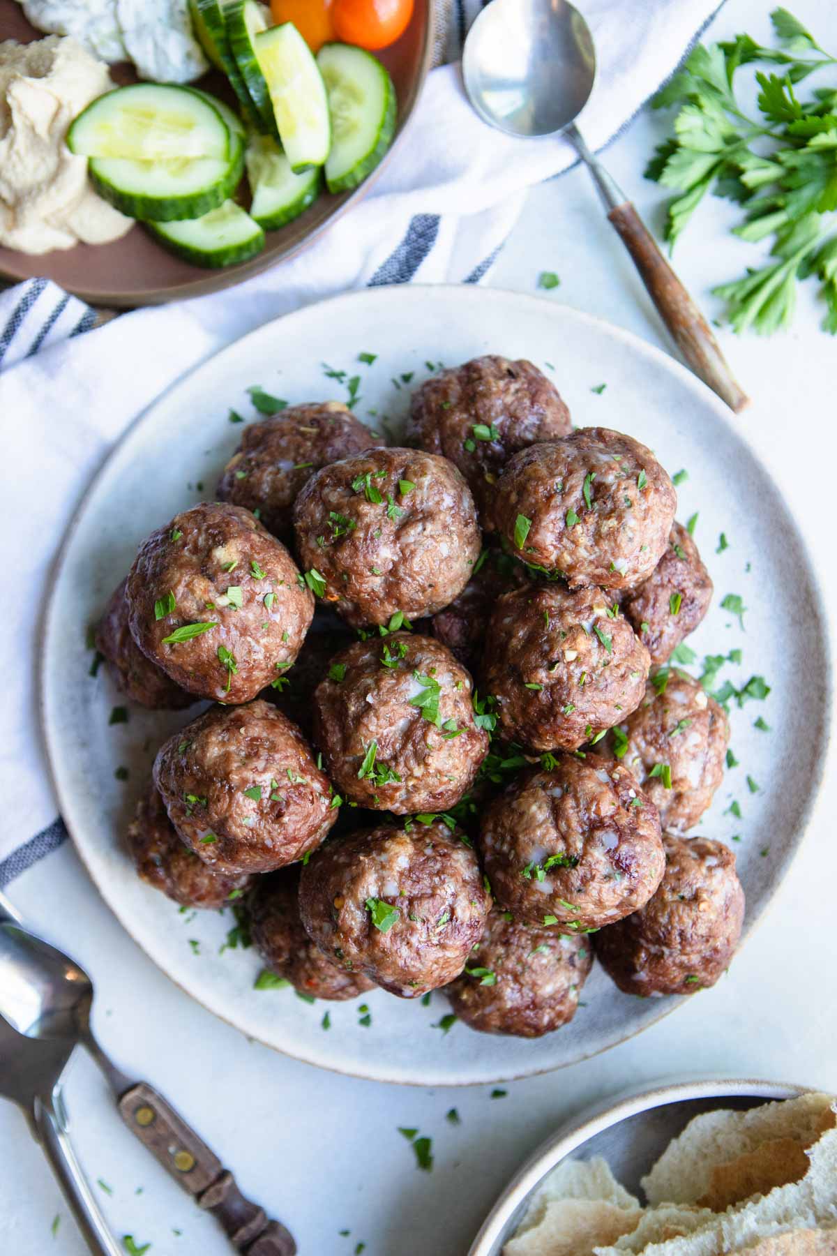 a plate filled with lamb and beef meatballs and garnished with parsley 