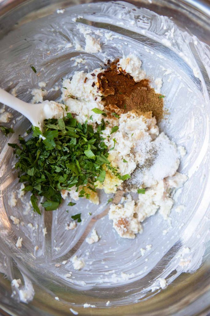 fresh and dried herbs added to a stainless mixing bowl to make a flavorful binder for lamb meatballs