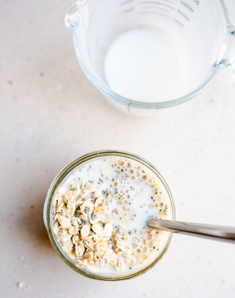 almond milk added to a mason jar with oats to make overnight oats